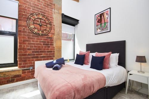 a bedroom with a large bed with a clock on the wall at The Grand Manhattan Apartment in Central Leeds in Leeds