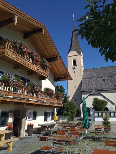 um edifício com mesas e cadeiras e uma torre do relógio em Mesnerwirt em Neukirchen am Teisenberg