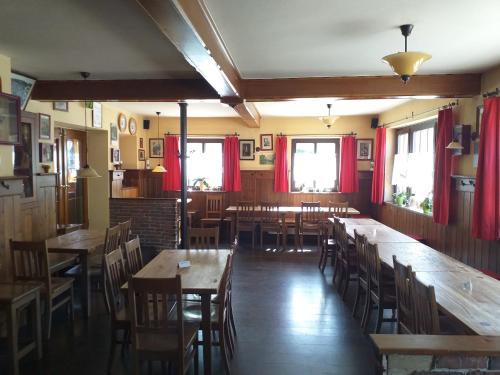um restaurante com mesas e cadeiras de madeira e cortinas vermelhas em Mesnerwirt em Neukirchen am Teisenberg