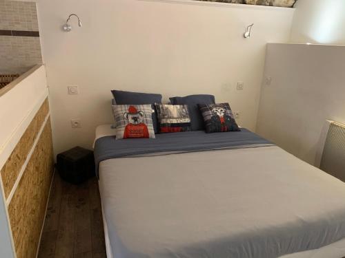 a bed in a small room with pillows on it at La Grotte in La Garde-Adhémar