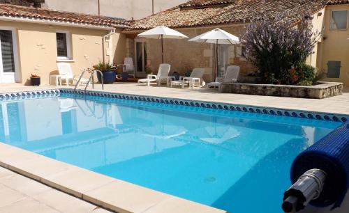 a large blue swimming pool with chairs and umbrellas at Maison Du Ruisseau in Malaville