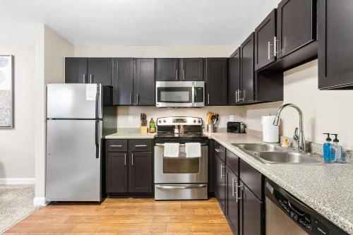 uma cozinha com armários pretos e electrodomésticos de aço inoxidável em Kasa Downtown South Bend em South Bend