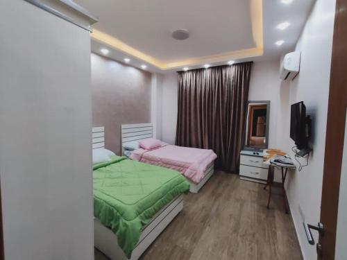 a bedroom with two beds and a television in it at Ramco For Furnished Apartments And Accommodation Compound Leila in Cairo