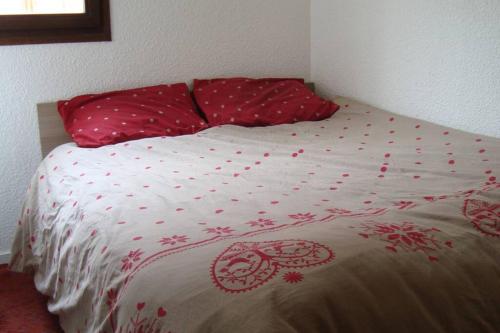 a bed with red and white sheets and pillows at Val Thorens 2 bedrooms 6 persons next slopes in Val Thorens