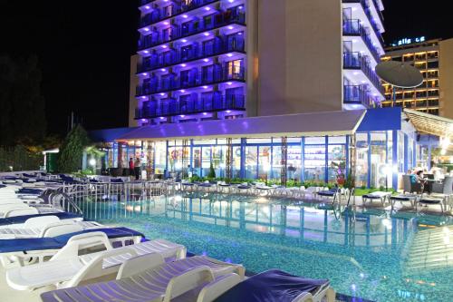 een zwembad met stoelen en 's nachts een gebouw bij Palace Hotel - Half Board in Sunny Beach
