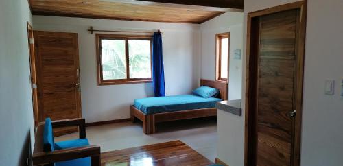 a small room with a blue bed and a window at Tagualodge Hostel Manglaralto in Manglaralto