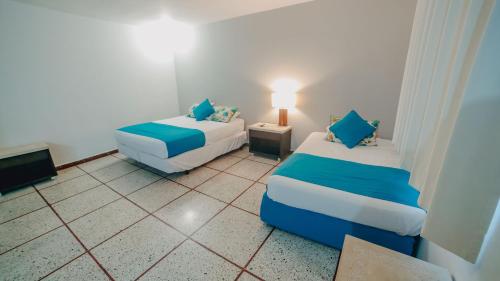a small room with two beds and a lamp at La Iguana de Santa Fe by Bernalo Hotels in Santa Fe de Antioquia