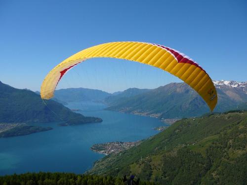 a yellow and red parachute flying over a lake at Hotel Europa - Sorico in Sorico