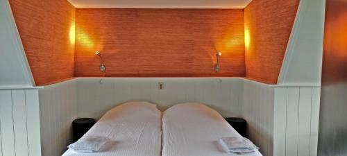 Bett in einem Zimmer mit zwei Kissen darauf in der Unterkunft Hotelhuisje Warmenhuizen #F in Warmenhuizen