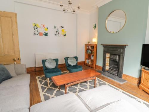 sala de estar con sofá, mesa y chimenea en 4 Tan Y Bryn Road, en Llandudno