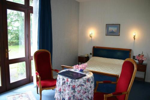 a bedroom with a bed and two chairs and a table at Domaine De Kerstinec/Kerland in Riec-sur-Bélon