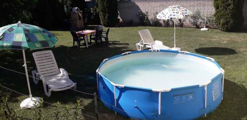 a blue hot tub with chairs and an umbrella at Holiday home in Balatonlelle 40449 in Balatonlelle