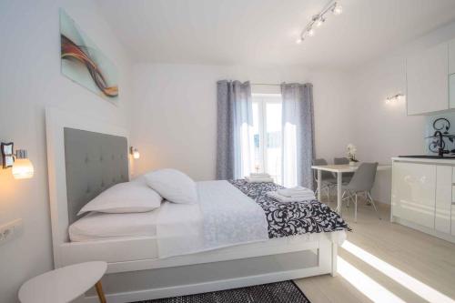 ein weißes Schlafzimmer mit einem großen Bett und einem Tisch in der Unterkunft Apartments in Rogoznica 40364 in Rogoznica