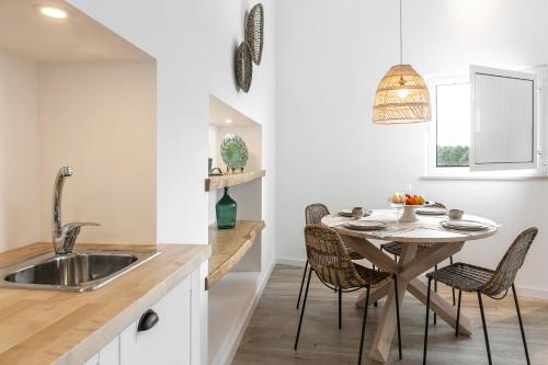 eine Küche mit einem Tisch, Stühlen und einem Waschbecken in der Unterkunft Pé no Campo Suites and Villa in Carvalhal