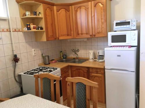 eine Küche mit Holzschränken und einem weißen Kühlschrank in der Unterkunft Apartments in Zalakaros 38691 in Zalakaros