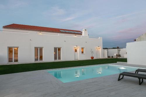 une maison blanche avec une piscine en face de celle-ci dans l'établissement Pé no Campo Suites and Villa, à Carvalhal