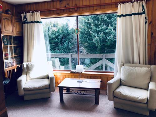 sala de estar con 2 sillas, mesa y ventana en Cabaña Departamento CERRO CATEDRAL Mínimo 5 NOCHES en San Carlos de Bariloche