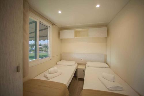 シルミオーネにあるMobilehomes in Sirmione/Gardasee 22177のベッド2台と窓が備わる小さな客室です。