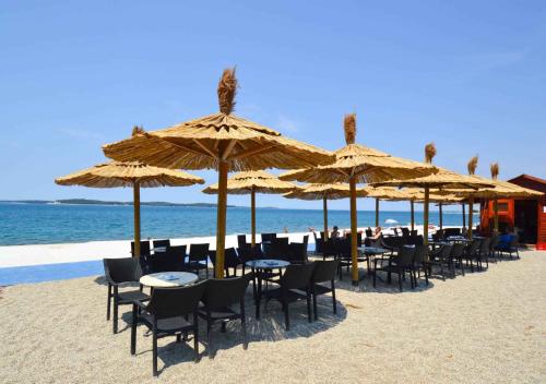 a group of tables and chairs under umbrellas on the beach at Apartment in Pula - Istrien 36865 in Veli Vrh