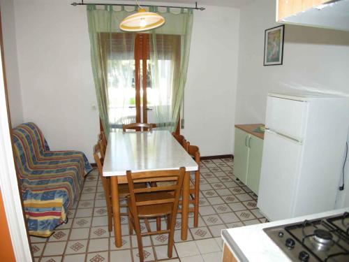 een keuken met een tafel, stoelen en een koelkast bij Apartments in Rosolina Mare 24945 in Rosolina Mare