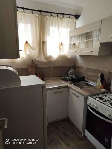 a kitchen with white cabinets and a stove and a window at Holiday home in Balatonmariafürdo 19443 in Balatonmáriafürdő