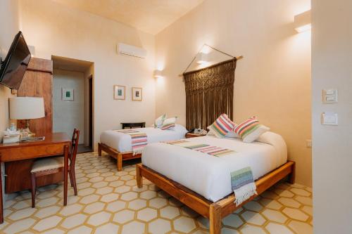 a hotel room with two beds and a desk at Waye Valladolid Centro - Sustainable, Authentic Experiences & Pet Friendly Boutique Hotel in Valladolid