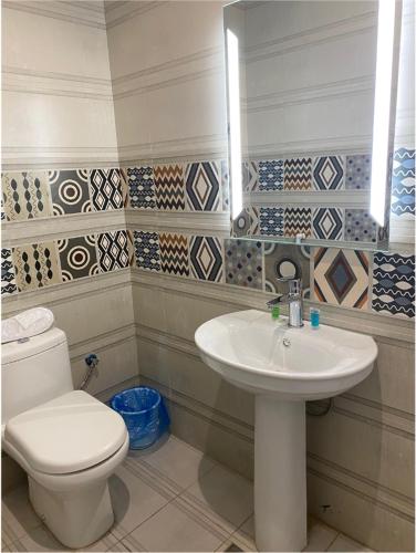 a bathroom with a white toilet and a sink at فندق كنان سويت in Sulţānah