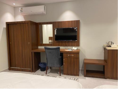 Zimmer mit einem Schreibtisch, einem TV und einem Stuhl in der Unterkunft فندق كنان سويت in Sulţānah