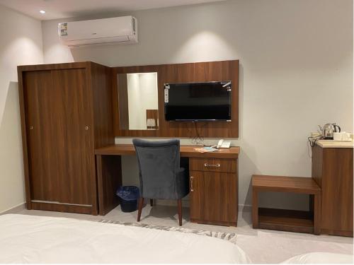 a room with a desk with a television and a chair at فندق كنان سويت in Sulţānah