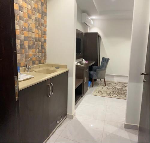 a kitchen with a sink and a desk with a chair at فندق كنان سويت in Sulţānah