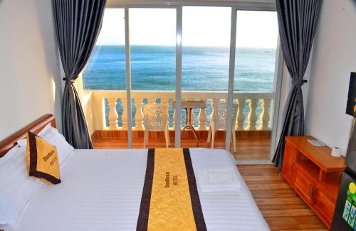 a bedroom with a bed and a view of the ocean at Sun Rose Hotel & Apartment in Xã Thang Tam