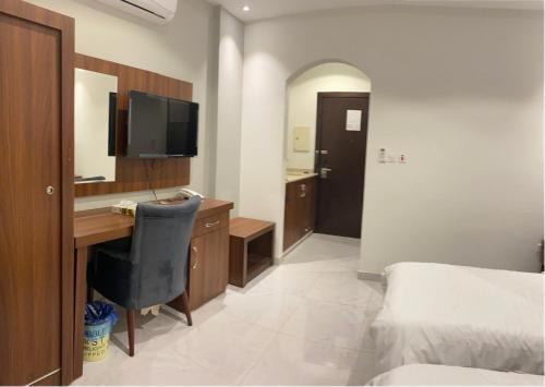 a bedroom with a desk and a bed and a television at فندق كنان سويت in Sulţānah