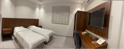 a hotel room with two beds and a television at فندق كنان سويت in Sulţānah