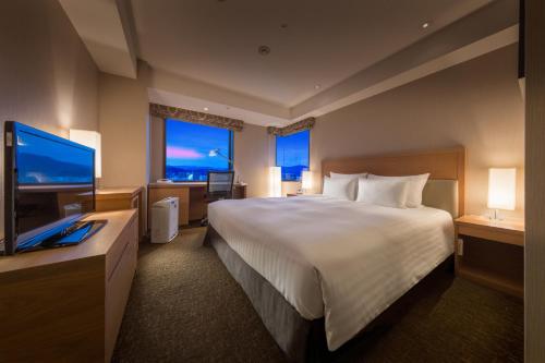 a hotel room with a bed and a flat screen tv at Hotel Associa Shizuoka in Shizuoka