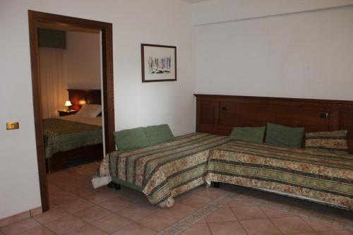 a hotel room with two beds and a mirror at Residence La Piscina in Isola del Gran Sasso dʼItalia