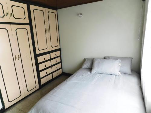 een kleine slaapkamer met een wit bed en kasten bij Los muiscas in Tunja