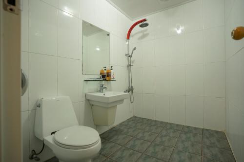 a white bathroom with a toilet and a sink at Jeju Stay Hotel in Jeju