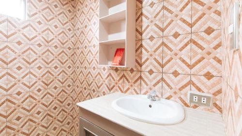 a bathroom with a sink and a tile wall at RedDoorz Plus at Canley Residential in Manila