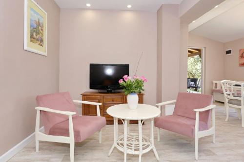 a living room with a table and chairs and a tv at HACIENDA MIA with yacuzzi,BBQ , free parking in Zadar