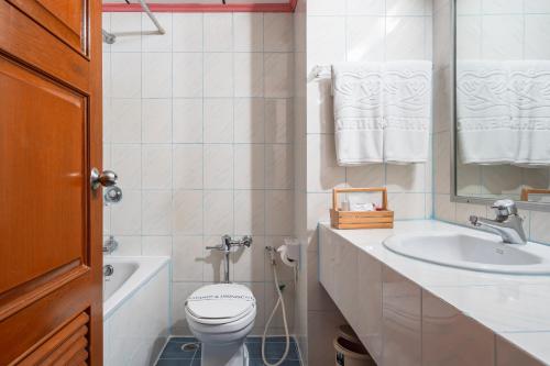 a white bathroom with a sink and a toilet at Elizabeth Hotel in Bangkok