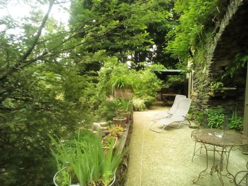 a patio with a table and chairs in a garden at Le mas des sources cevenol Le chambon in Le Chambon
