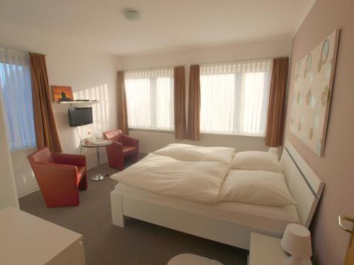 ランゲオークにあるPension Friedrich Vossのベッドルーム1室(白いベッド1台、椅子2脚付)