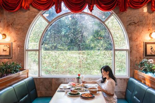a woman sitting at a table in front of a window at Elizabeth Hotel in Bangkok