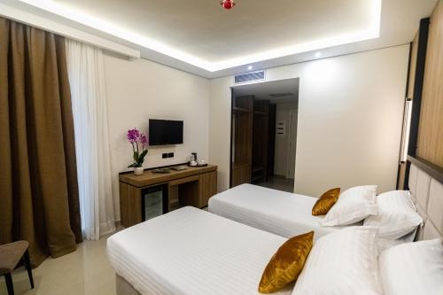a hotel room with two beds and a television at Kraal Hotel Vlore in Vlorë