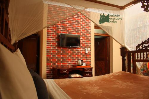 a bedroom with a brick wall with a tv on a fireplace at LUSHOTO EXECUTIVE LODGE in Lushoto
