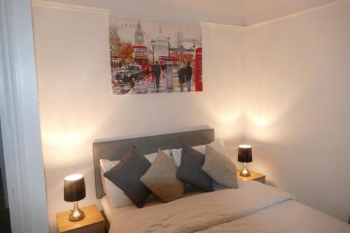 a bedroom with a bed with two lamps and a painting at Fully equipped 1 bed flat in Croydon in London