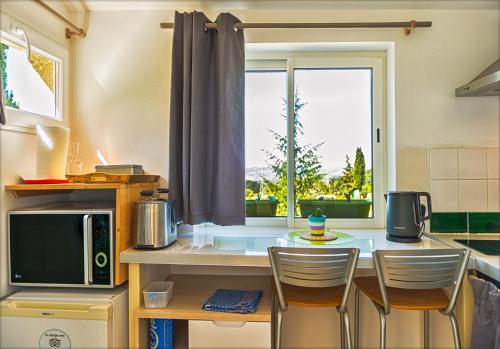 une cuisine avec un comptoir avec des chaises et une fenêtre dans l'établissement Ecuries Sainte Croix, à Carcassonne