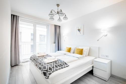 a white bedroom with a bed and a window at Bella Casa Premium Apartment - 30 Pszczelna in Krakow