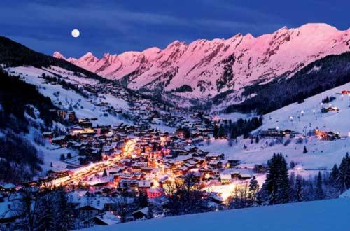 a town in the snow at night in the mountains at Chalet-Hôtel du Borderan in La Clusaz