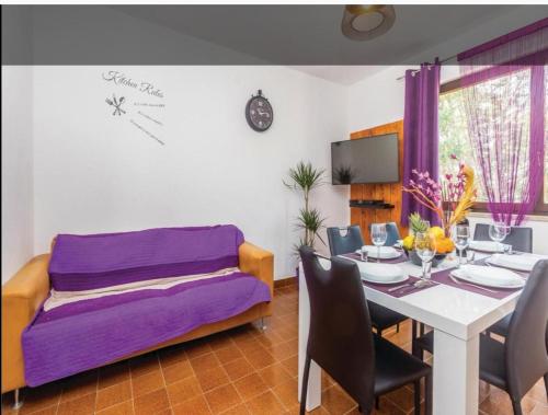 a dining room with a table and a purple couch at Apartman Ana in Draga Bašćanska